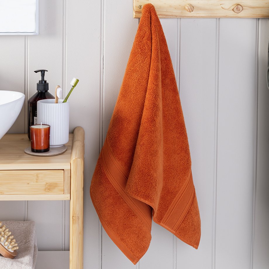 Habitat supersoft hand towel in copper colour hung next to a sink.